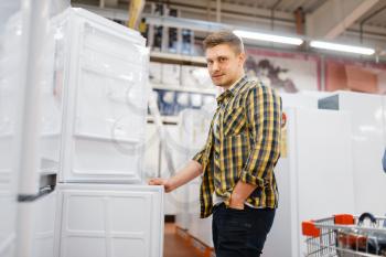 Man choosing refrigerator in electronics store. Male person buying home electrical appliances in market