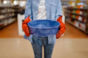 Woman in gloves holds bowl, houseware store. Female person buying home goods in market, lady in kitchenware supply shop