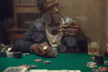 Two poker players place bets on gaming table with green cloth in casino. Games of chance addiction, risk, gambling house. Men leisures with whiskey and cigars