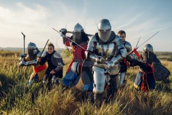 Medieval knights in armor and helmets fight with sword and axe, great tournament. Armored ancient warrior in armour posing in the field