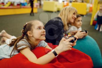 Children plays a game console in the entertainment center. Girl and boy leisures on holidays, childhood happiness, happy kids