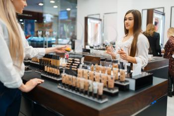 Cosmetician at the counter and woman in cosmetics store. Luxury beauty shop salon, female customer and beautician in fashion market