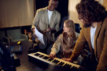 Male and female performers, recording studio interior on background. Synthesizer and audio mixer, musician workplace, creative process