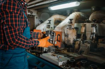 Carpenter in uniform near woodworking machine, lumber industry, carpentry. Wood processing on factory, forest sawing in lumberyard