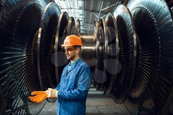 Male engineer checks turbine impeller vanes on factory. Industrial production, metalwork engineering, machines manufacturing