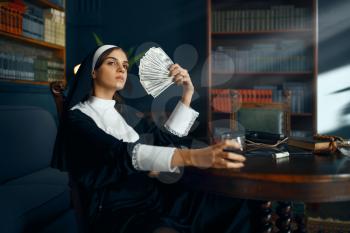 Sexy nun in a cassock holding a fan of dollars and drinks wine, vicious desires. Corrupt sister in the monastery, religion and faith, sinful religious people, attractive sinner