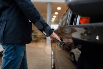 Man looking on transport interior in car dealership. Customer in new vehicle showroom, male person buying automobile, auto dealer business