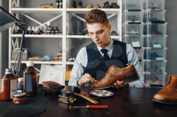 Shoemaker polishes the shoe, footwear repair service. Craftsman skill, shoemaking workshop, master works with boots, cobbler