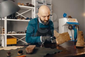 Shoemaker fix the shoe, footwear repair service. Craftsman skill, shoemaking workshop, master works with boots, cobbler job
