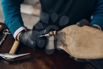 Bootmaker repairing the shoe, footwear repair service. Craftsman skill, shoemaking workshop, master works with boots, cobbler job