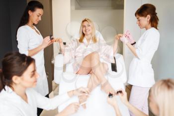 Four masters and one woman, pedicure and manicure procedure in beauty salon. Professional beauticians and female customer, toenail and fingernail care in spa studio
