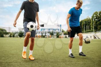 Male soccer players stuffs the ball with their feet on the field. Footballers on outdoor stadium, team workout before game