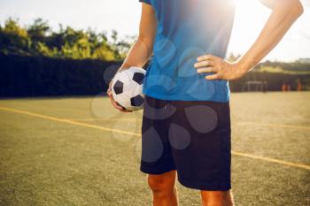 Male soccer player with ball standing on the field. Footballer on outdoor stadium, workout before game, football training