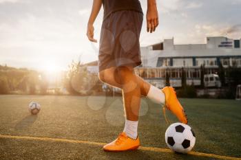 Soccer player with ball on the field at sunrise. Footballer on outdoor stadium, workout before game, football training