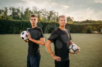 Two male soccer players holding balls in hands on the field. Footballer on outdoor stadium, workout before game, football training