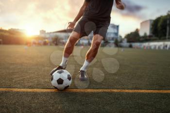 Male football player hits the ball on the field. Footballer on outdoor stadium, workout before competition, soccer training