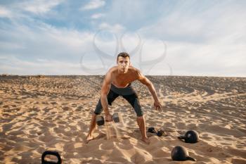 Sportsman doing exercises with dumbbells in desert at sunny day. Strong motivation in sport, strength outdoor training