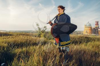 Female medieval knight poses in armor opposite the castle, great tournament. Armored ancient warriors in armour posing in the field