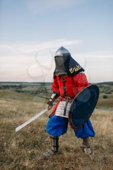 Medieval knight with sword poses in armour, great fighter. Armored ancient warriors in armor posing in the field