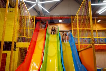 Little children having fun on inflatable slide, playground in entertainment center. Play area indoors, playroom