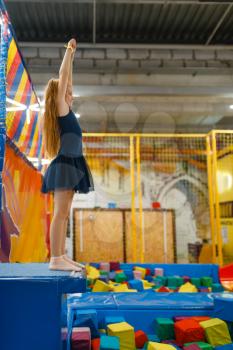 Adorable girl jumping on kids trampoline, playground in entertainment center. Play area indoors, playroom