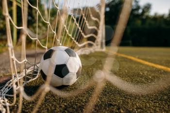 Soccer ball in the gate net, nobody. Football on outdoor stadium, sport game or goal concept