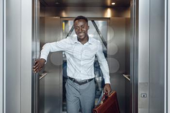 Black businessman goes into the elevator in office building. Successful business person, black man in formal wear, shopping center