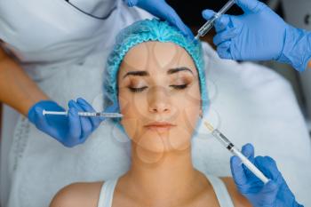 Cosmetician hands in gloves holds syringes with botox injection at female patient face. Rejuvenation procedure in beautician salon. Doctor and woman, cosmetic surgery against wrinkles