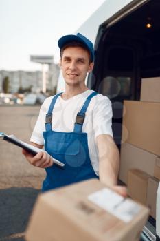 Deliveryman in uniform gives parcel, carton boxes in the car, delivery service. Man standing at cardboard packages in vehicle, male deliver, courier or shipping job