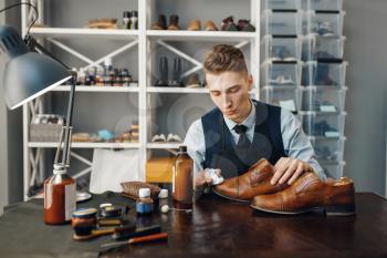 Shoemaker polishes the shoe, footwear repair service. Craftsman skill, shoemaking workshop, master works with boots, cobbler shop