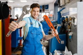 Plumber shows pipe wrenches at the showcase in plumbering store. Man buying sanitary engineering tools and equipment in shop