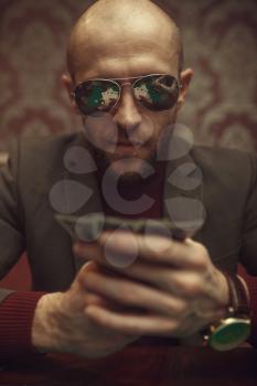 Professional poker player in sunglasses playing in casino. Games of chance addiction. Man with cards in hands leisures in gambling house