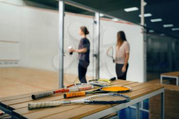 Squash rackets on the table, players on background. Youth on training, active sport hobby, fitness workout for healthy lifestyle