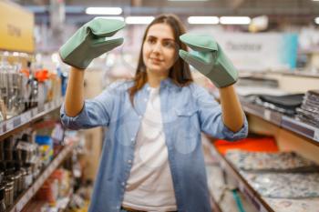 Young woman in heat-resistant gloves, houseware store. Female person buying home goods in market, lady in kitchenware supply shop