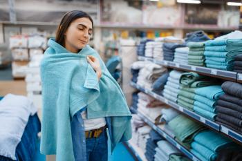 Young woman wrapped herself in a towel, bed linen store. Female person buying home goods in market, lady in bedding shop