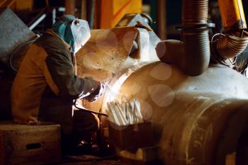 Welder in mask works with metal construction on factory, welding skill. Metalworking industry, industrial manufacturing of steel products