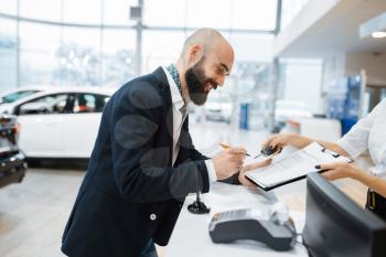 Man signs a contract to buy a new auto in car dealership. Customer and saleswoman in vehicle showroom, male person buying transport, automobile dealer business