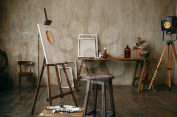 Painter tools and easel in art studio, nobody. Creative artist equipment, workplace. Atelier or workshop interior