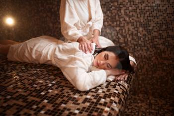 Female masseuse makes massage to woman in sauna, turkish bath, hamam. Healthcare, skincare and body care
