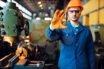 Male worker hands holds detail, lathe on background, plant. Industrial production, metalwork engineering, power machines manufacturing