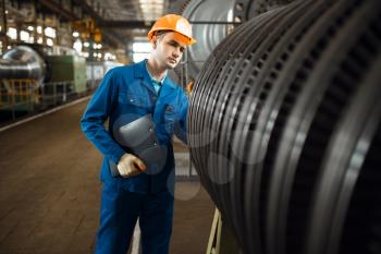 Male worker with notebook, large turbine on background, plant. Industrial production, metalwork engineering, power machines manufacturing