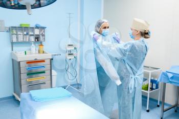 Female surgeon and assistant in operating room, preparing for surgery operation. Doctor in uniform, medical clinic worker, medicine and health, healthcare in hospital
