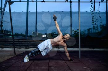 Strong man doing stretch exercise, street workout, crossfit. Fitness training on sports ground outdoor, male person pumps muscles, active urban lifestyle