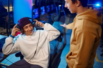 Two young gamers talking at the monitor in gaming club. Virtual entertainment, e-sport tournament, cybersport lifestyle. Male person leisures in internet cafe