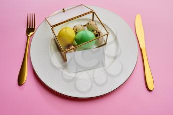 Easter eggs on plate and tableware on pink background. Spring tree blossom and paschal food, fresh floral decoration for holiday celebration, event symbol