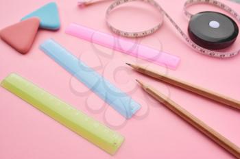 Office stationery supplies closeup, pink background. School or education accessories, writing and drawing tools, pencils and rubbers, ruler and paper clips