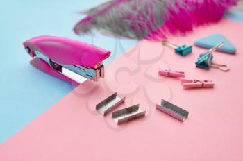 Stapler and clips closeup, blue background. Office stationery supplies, school or education accessories, writing and drawing tools
