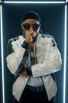 Stylish rapper in sunglasses, dark background. Hip-hop performer, rap singer, break-dance performing, entertainment lifestyle