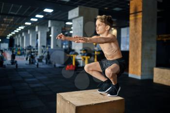 Athletic boy doing balance exercise on pedestal in gym. Youngster on training in sport club, healthcare and healthy lifestyle, schoolboy on aerobics workout, sportive youth