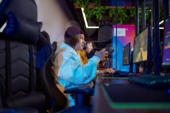 Two young gamers play in video game club. Virtual entertainment, e-sport tournament, cybersport lifestyle. Male person leisures in internet cafe